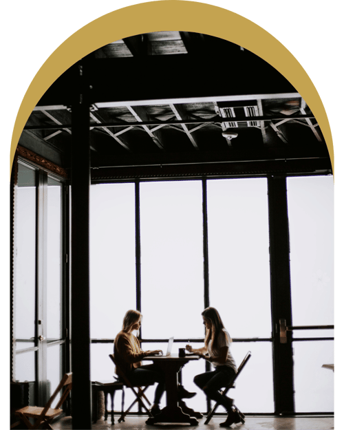 Two women collaborating on laptops in a bright, modern workspace, symbolizing the collaborative and tailored approach of The Maven of Momentum Method.