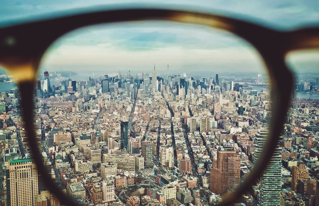 A panoramic view of New York City through a pair of glasses, highlighting skyscrapers and urban landscape. A panoramic view of New York City through a pair of glasses, highlighting skyscrapers and urban landscape.