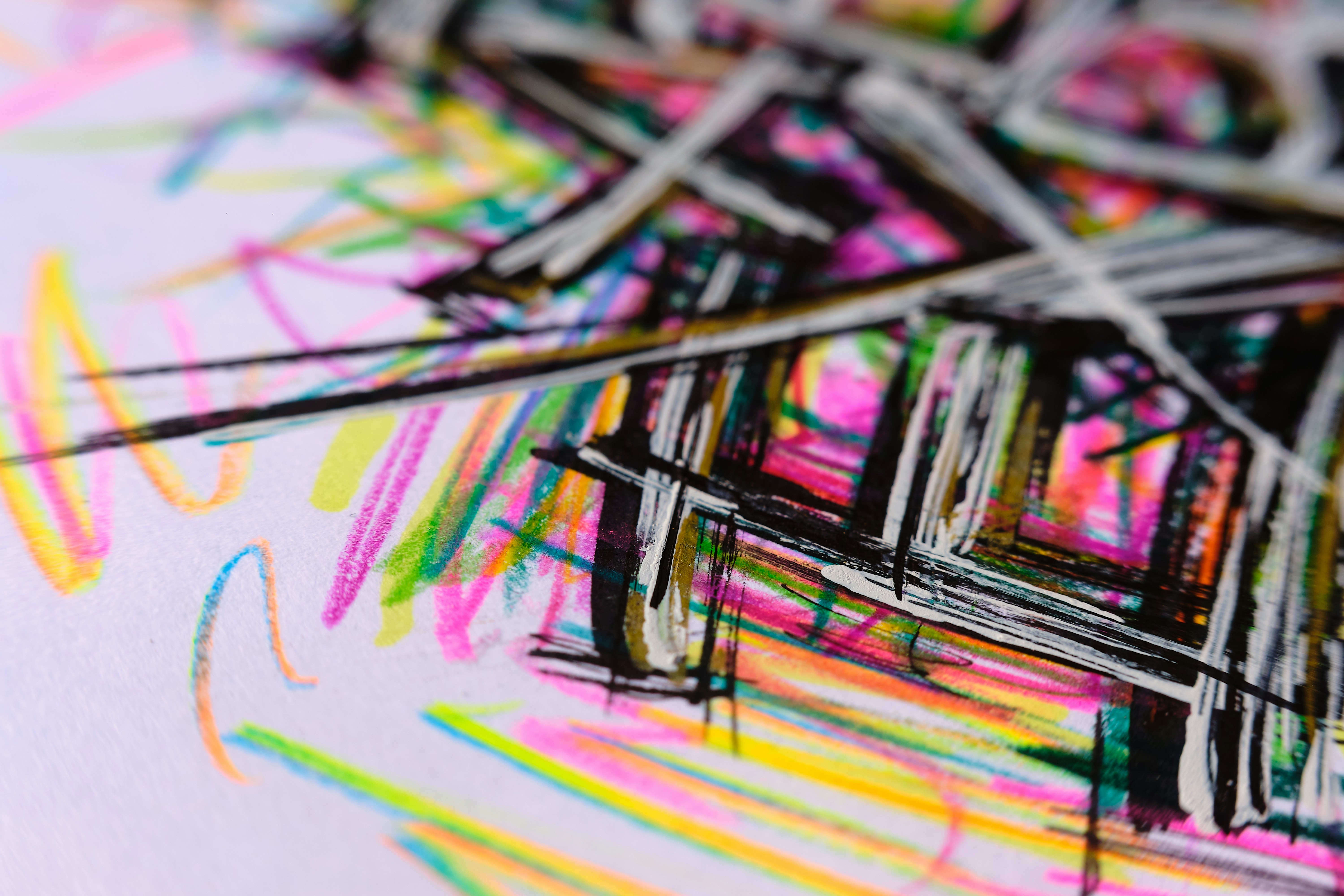 Close-up of vibrant, abstract artwork featuring bold black lines overlaid on a splash of bright colors like pink, yellow, and green.